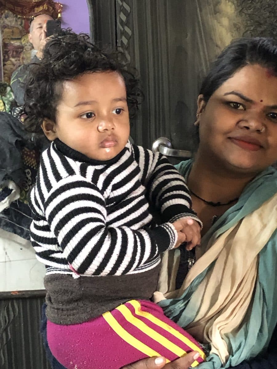 Woman holding a young child inside the family home.